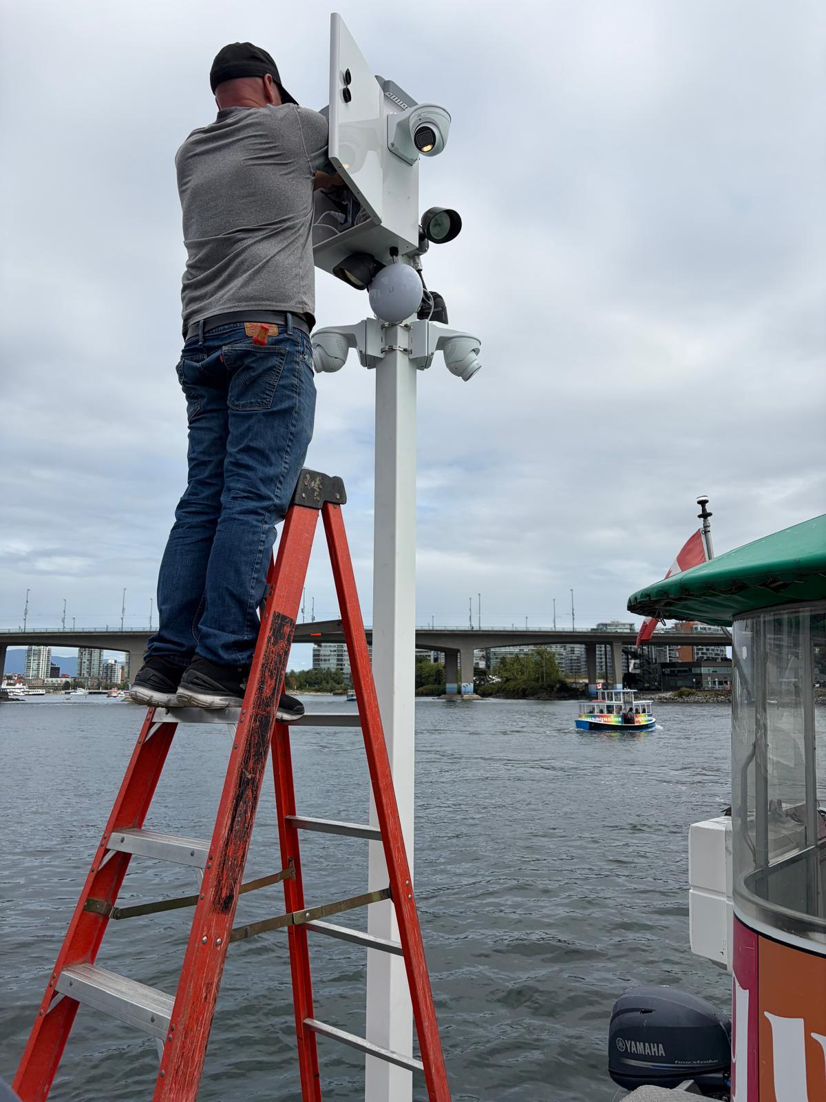 An Allied technician terminating cameras on a dock-mounted pole at a Vancouver marina