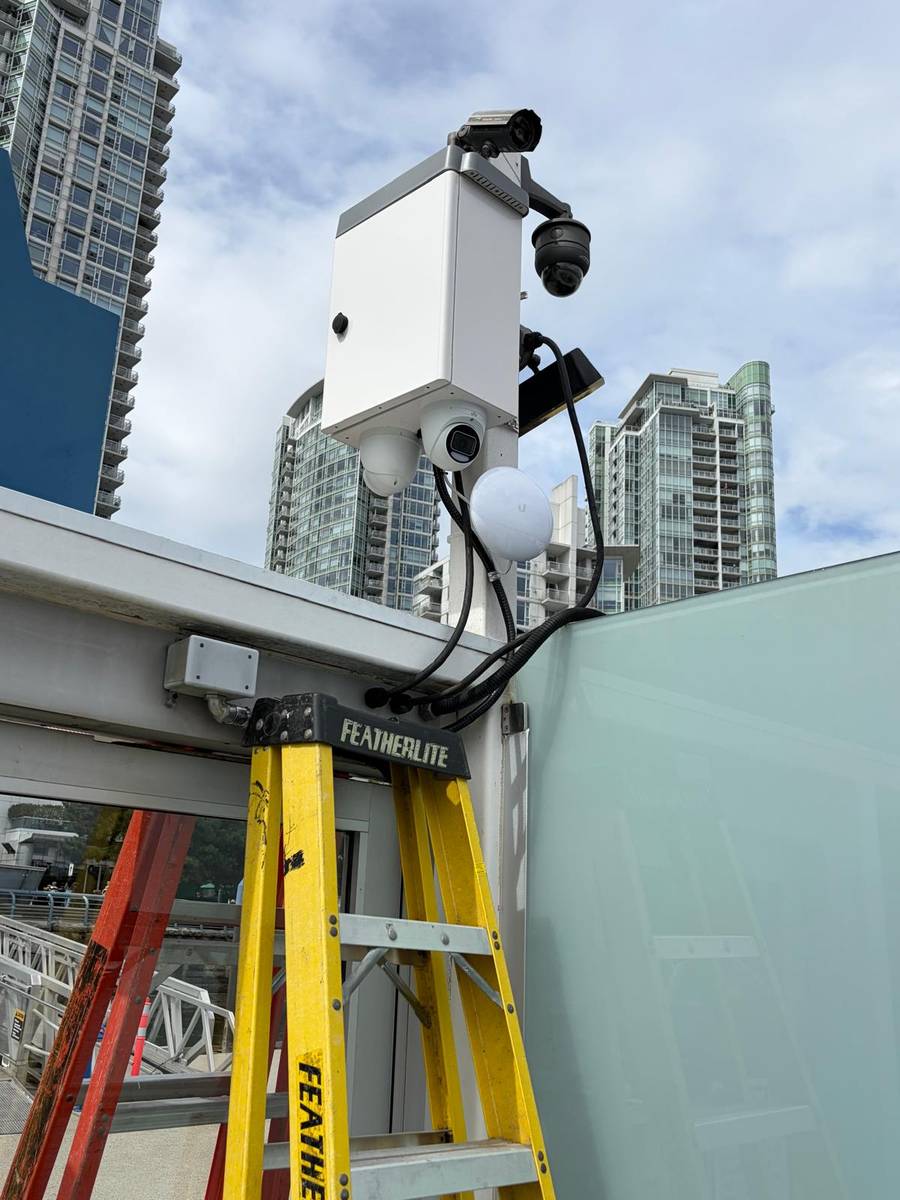 Technician working on a camera pole with residential towers behind